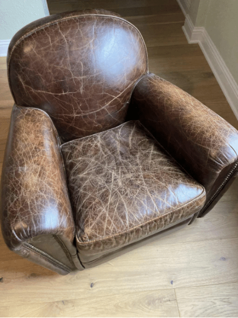 Animated GIF showing the transformation of a distressed brown leather armchair. The cracked and faded leather gradually becomes darker, smoother, and more vibrant as conditioner is applied, highlighting the restoration process and rejuvenated finish.