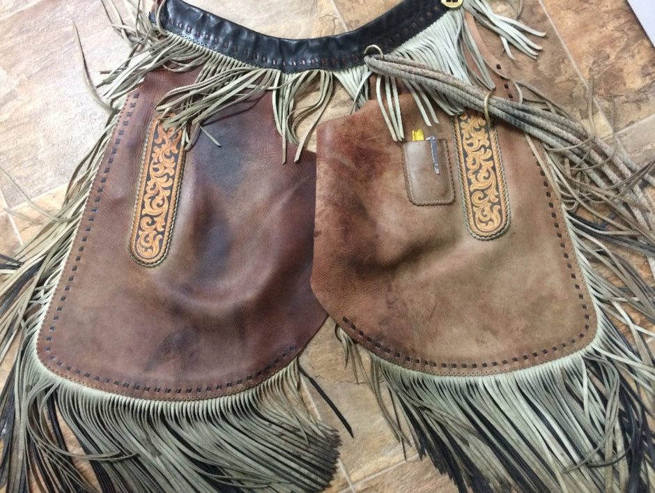A pair of riding chaps laying on a table. The right side has been treated with Leather Better restoring the moisture and colour, while the left side is untreated and looking dull and stained.