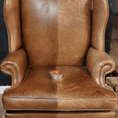Load image into Gallery viewer, A fancy tan leather chair with a can of Leather better on the seat. The left side of the chair has been treated with Leather better, the right side shows the scratched and faded before.