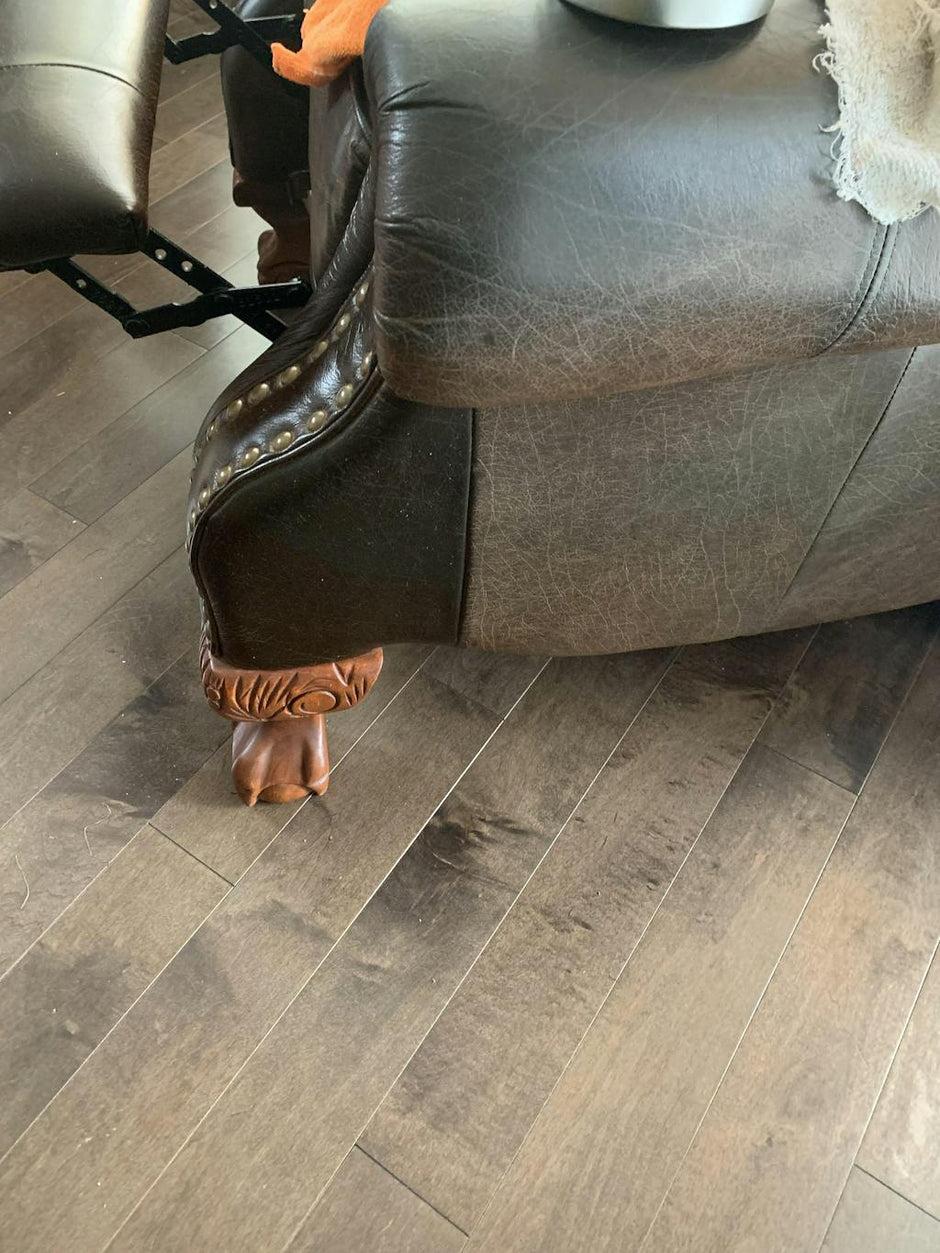 A black leather recliner chair with a fancy wooden chair leg. Part of the chair has been treated with Leather better, while the other part of the chair is untreated.
