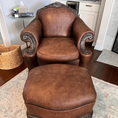 Load image into Gallery viewer, An oversized brown armchair with wood detailing after being treated with Leather Better. The colour is restored and customer also included the ottoman in the after photo.