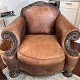 Load image into Gallery viewer, An oversized brown armchair with wood detailing prior to being treated with Leather Better with scuff marks and colour faded.