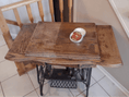 Load image into Gallery viewer, Sewing machine desk on a tile floor with iron legs. Right side of the desk has been treated with Leather better, and the left side untreated to showcase the results. A can of Leather better sits on open on the desk.