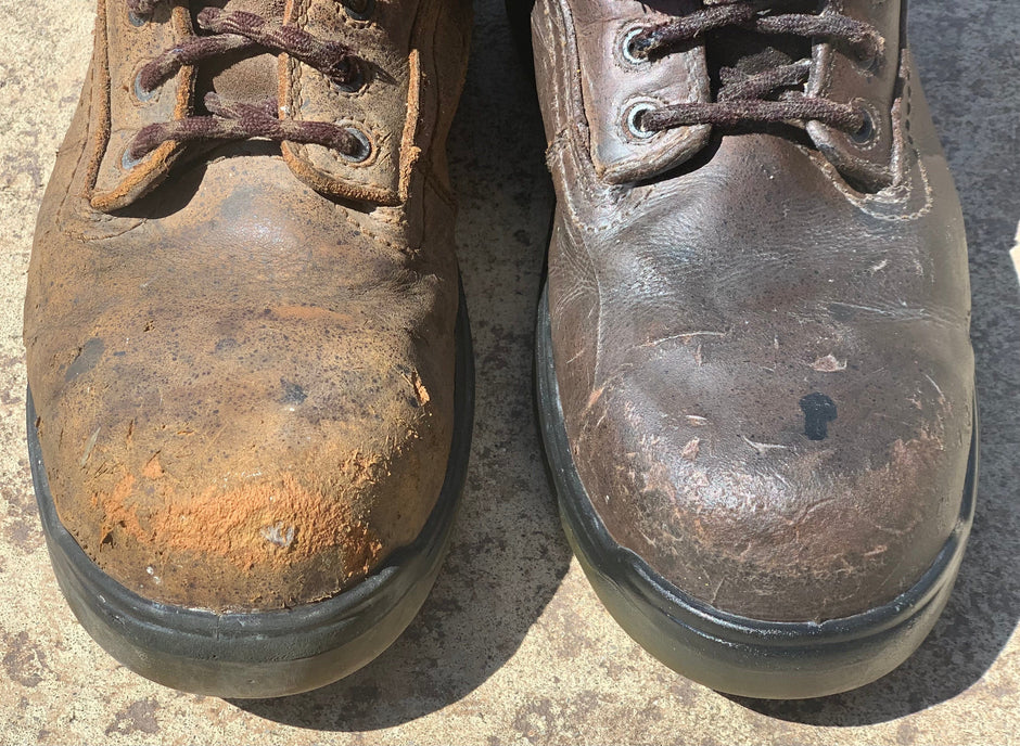 Close-up of two heavily worn leather work boots, shown side by side to illustrate restoration results. The right boot is extremely dry, cracked, and flaking with orange-toned damage, while the left boot has been conditioned, showing improved texture, deeper colour, and reduced surface damage.