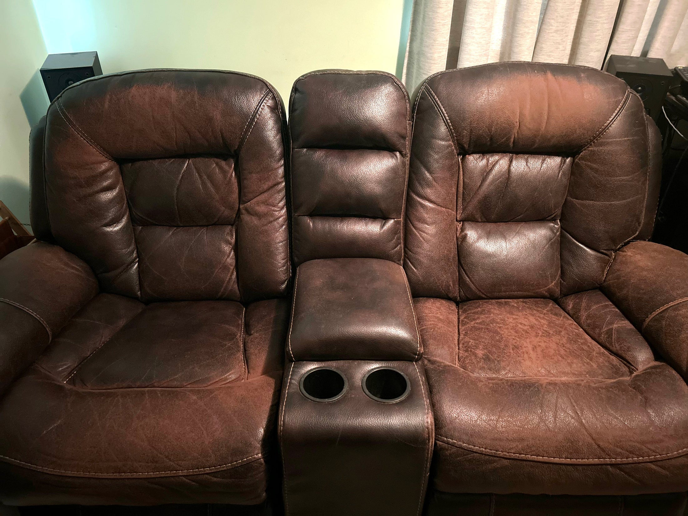 A faded and worn dark brown leather love seat recliner prior to being treating with Leather Better.