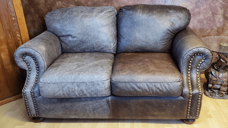 Dark brown leather love seat showcasing the right side before treatment and the left side after treatment with Leather Better.  The results are dramatic with the colour restored and scratches disappeared!